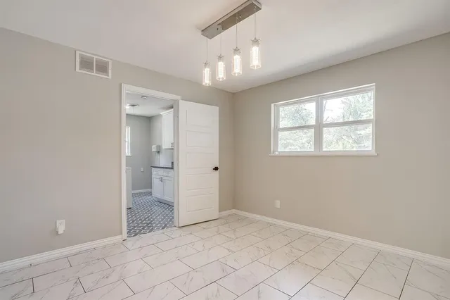 a view of an empty room with window and chandelier fan
