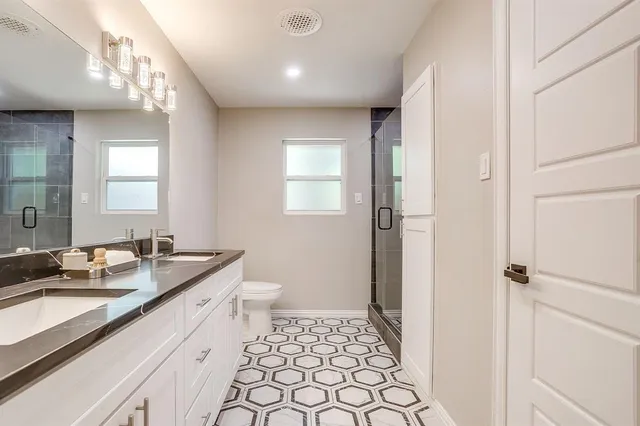 a spacious bathroom with a double vanity sink a toilet and a mirror