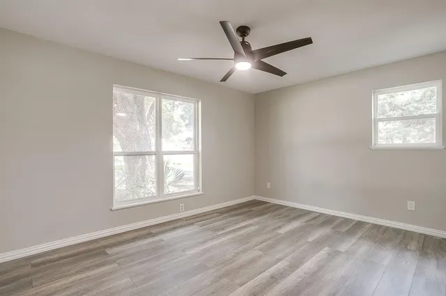 a view of empty room with wooden floor and fan