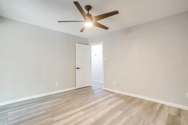 an empty room with wooden floor and ceiling fan