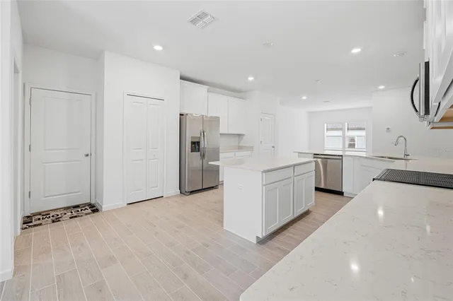 a large kitchen with a refrigerator a sink and cabinets