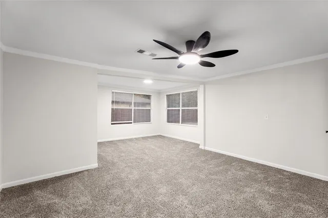 an empty room with ceiling fan and windows