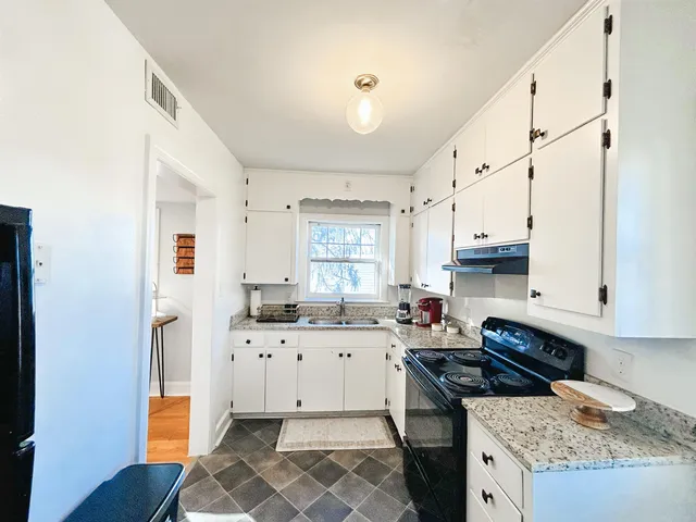a kitchen with granite countertop a sink stove and cabinets