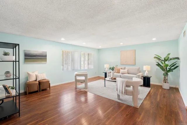a living room with furniture a potted plant and open kitchen view