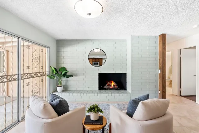 a living room with furniture a fireplace and a floor to ceiling window