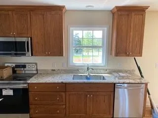 a kitchen with granite countertop stainless steel appliances a sink window and cabinets