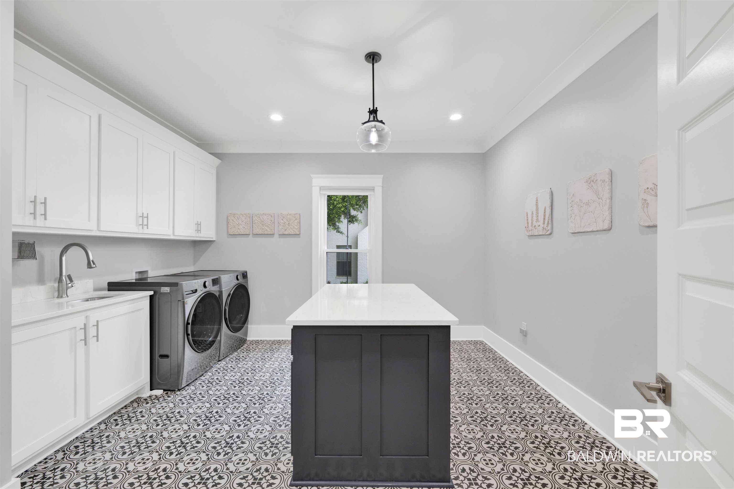 21702 Pillars Street Fairhope, AL 36532 - Photo 18 of 54 Dedicated utility space featuring patterned floor tile, white shaker-style cabinetry, and a central island with a solid surface countertop