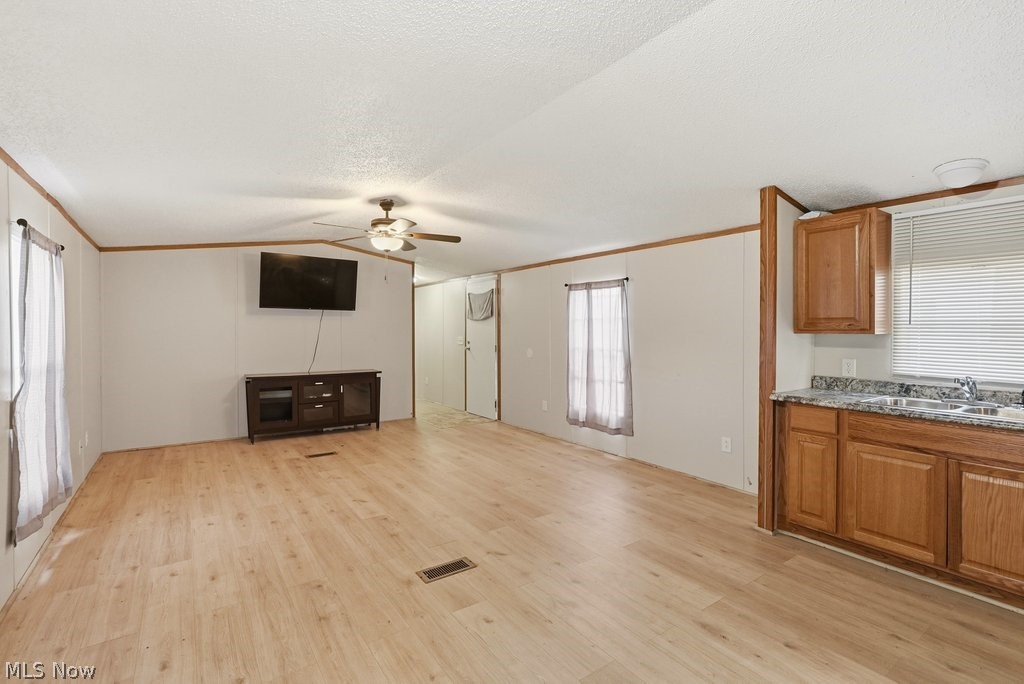 6507 Robby Lane Ravenna, OH 44266 - Photo 7 of 25 Unfurnished living room with ornamental molding, ceiling fan, and light wood-type flooring