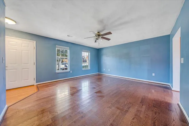 an empty room with wooden floor and windows
