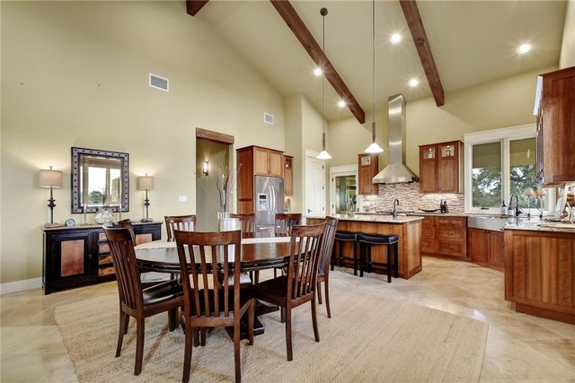 633 Trails End Road Johnson City, TX 78636 - Photo 10 of 29 Beamed ceilings and stone-look tile flooring elevate this expansive open kitchen and dining space.