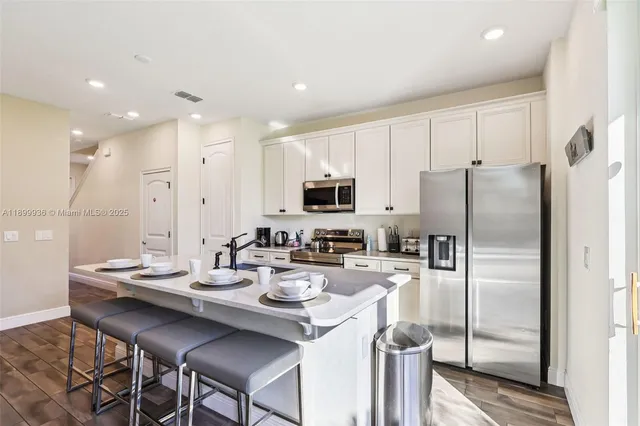 a kitchen with a refrigerator a stove a sink and chairs
