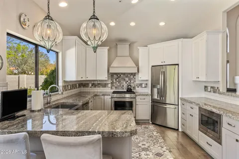 a kitchen with stainless steel appliances granite countertop a sink a stove a refrigerator cabinets and chairs