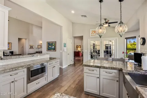 a large kitchen with stainless steel appliances granite countertop a lot of white cabinets and a wooden floors