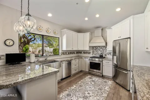 a kitchen with granite countertop stainless steel appliances a stove refrigerator sink and microwave
