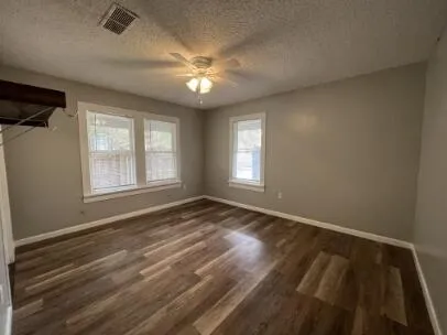 a view of empty room with wooden floor and fan