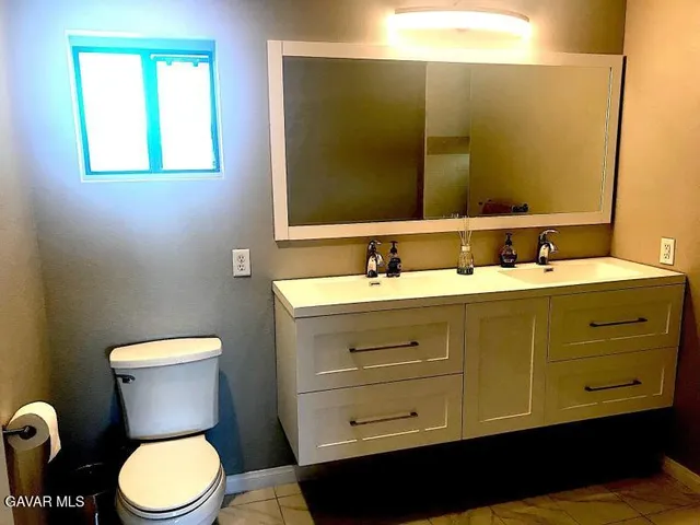 a bathroom with a toilet sink vanity and mirror