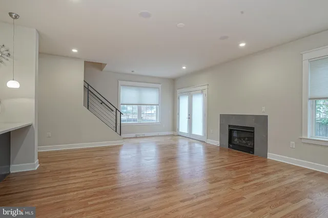 an empty room with wooden floor fireplace and windows