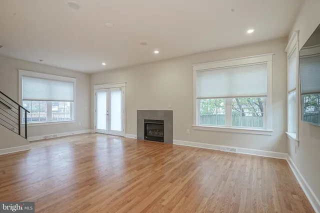 an empty room with wooden floor fireplace and windows