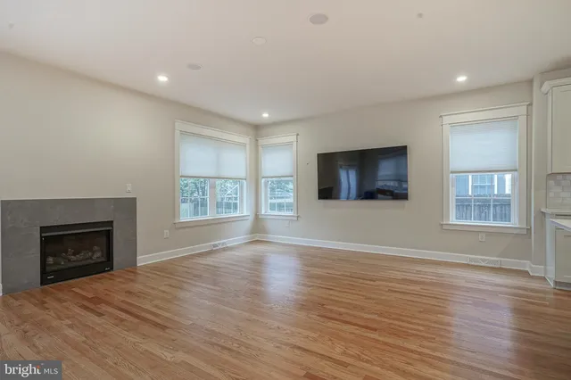 an empty room with wooden floor fireplace and windows