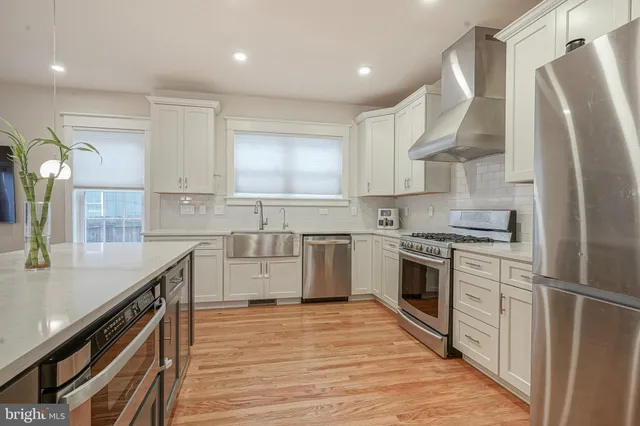 a kitchen with stainless steel appliances granite countertop a sink a stove and a refrigerator