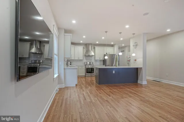 a open kitchen with kitchen island a sink dishwasher stove with wooden floors
