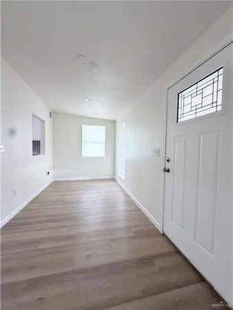 an empty room with wooden floor fan and windows