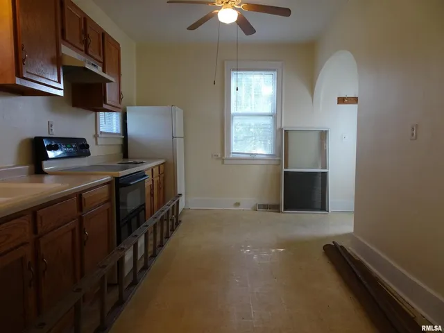 a kitchen with stainless steel appliances granite countertop a sink a stove top oven a chimney and a refrigerator