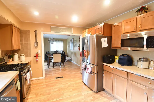 a kitchen with stainless steel appliances kitchen island granite countertop a refrigerator a stove top oven and a sink with couches