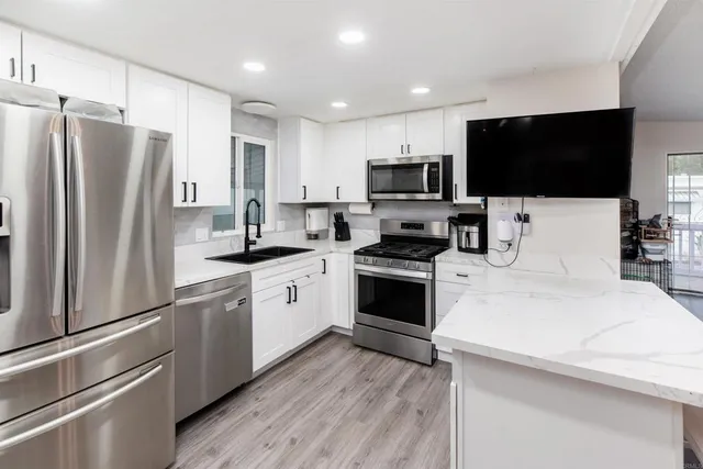 a kitchen with a sink a microwave a refrigerator and cabinets