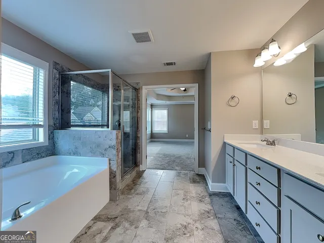 a spacious bathroom with a tub sink and mirror