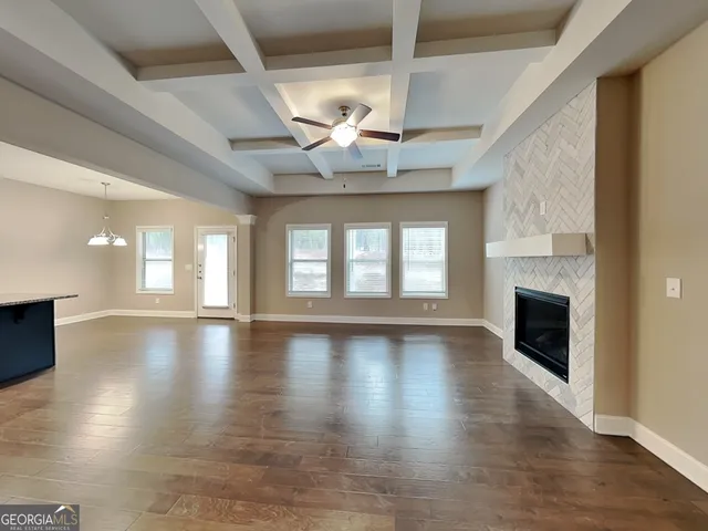 an empty room with wooden floor fireplace and windows