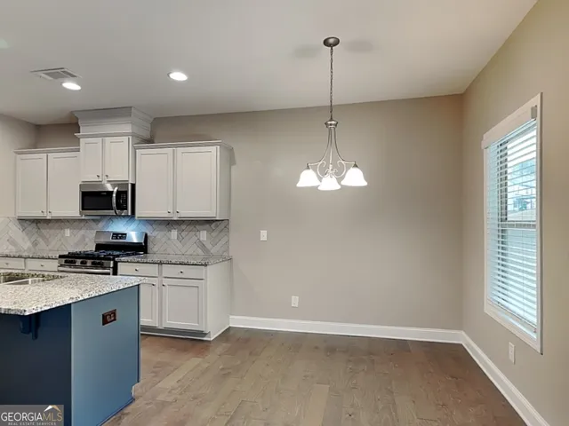 a kitchen with stainless steel appliances a stove a sink dishwasher a refrigerator and white cabinets with wooden floor