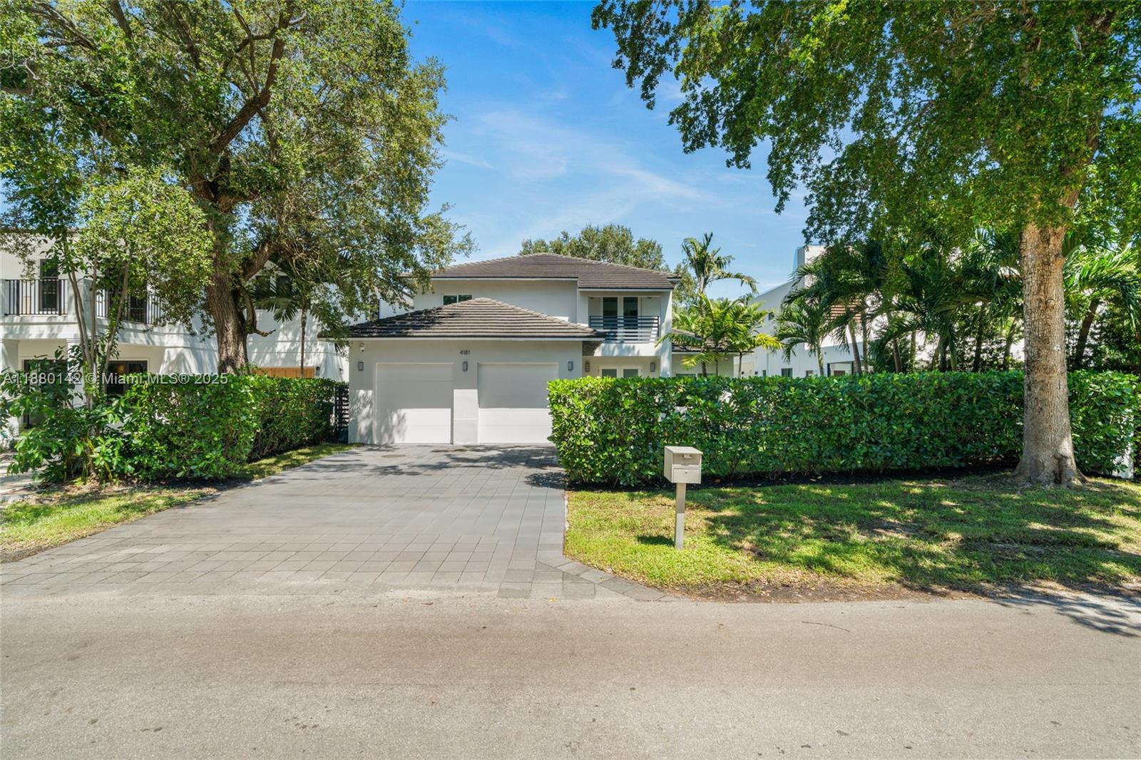 a view of a house with a small yard and large trees