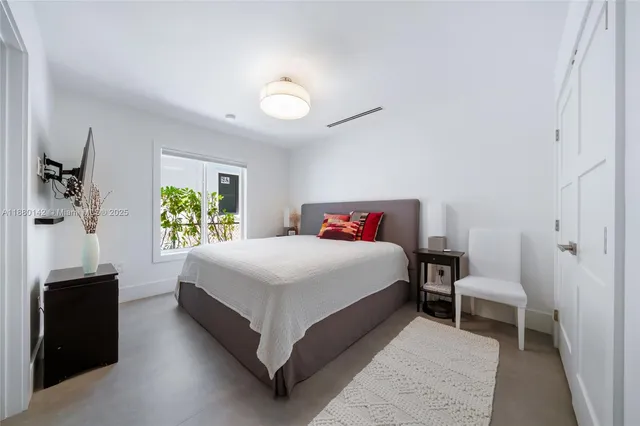 a bedroom with a bed and a flat tv screen on dresser