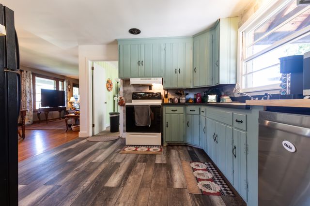 a kitchen with stainless steel appliances a stove top oven a sink dishwasher and cabinets with wooden floor