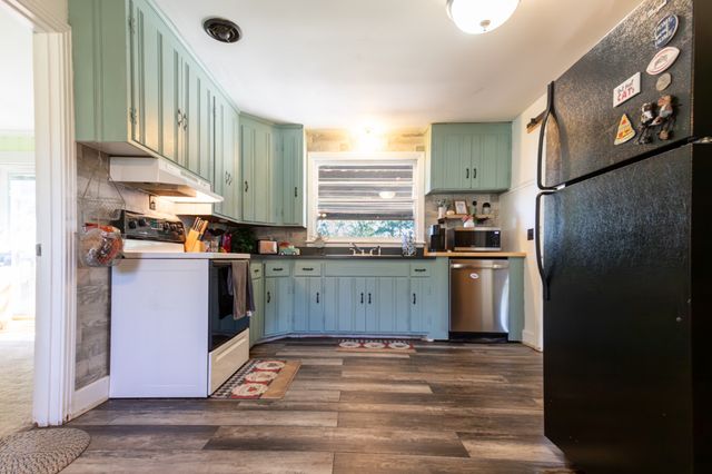 a kitchen with stainless steel appliances granite countertop a refrigerator a sink and a stove