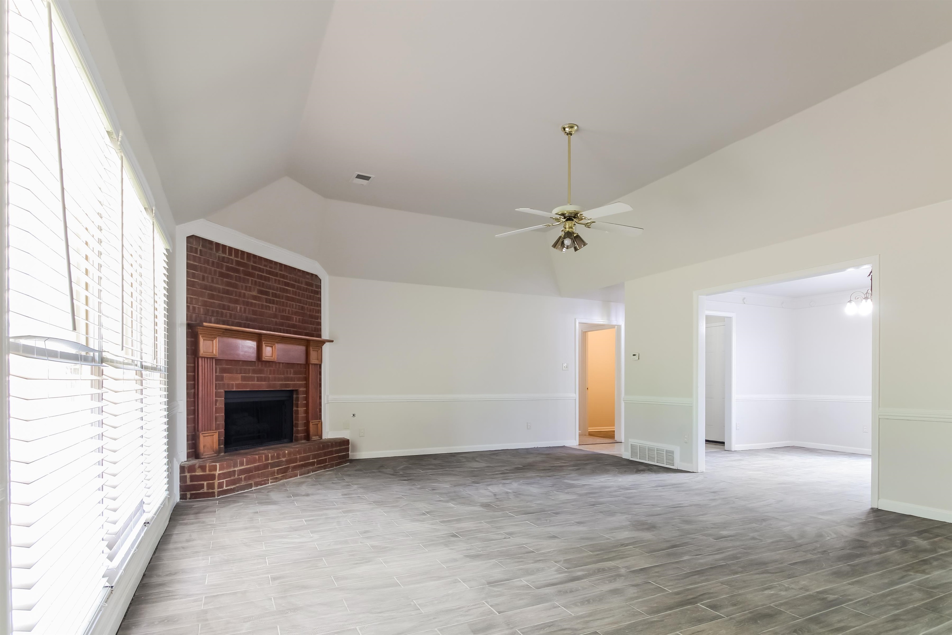 8859 Raspberry Lane Memphis, TN 38016 - Photo 5 of 16 Unfurnished living room featuring lofted ceiling, a brick fireplace, and ceiling fan