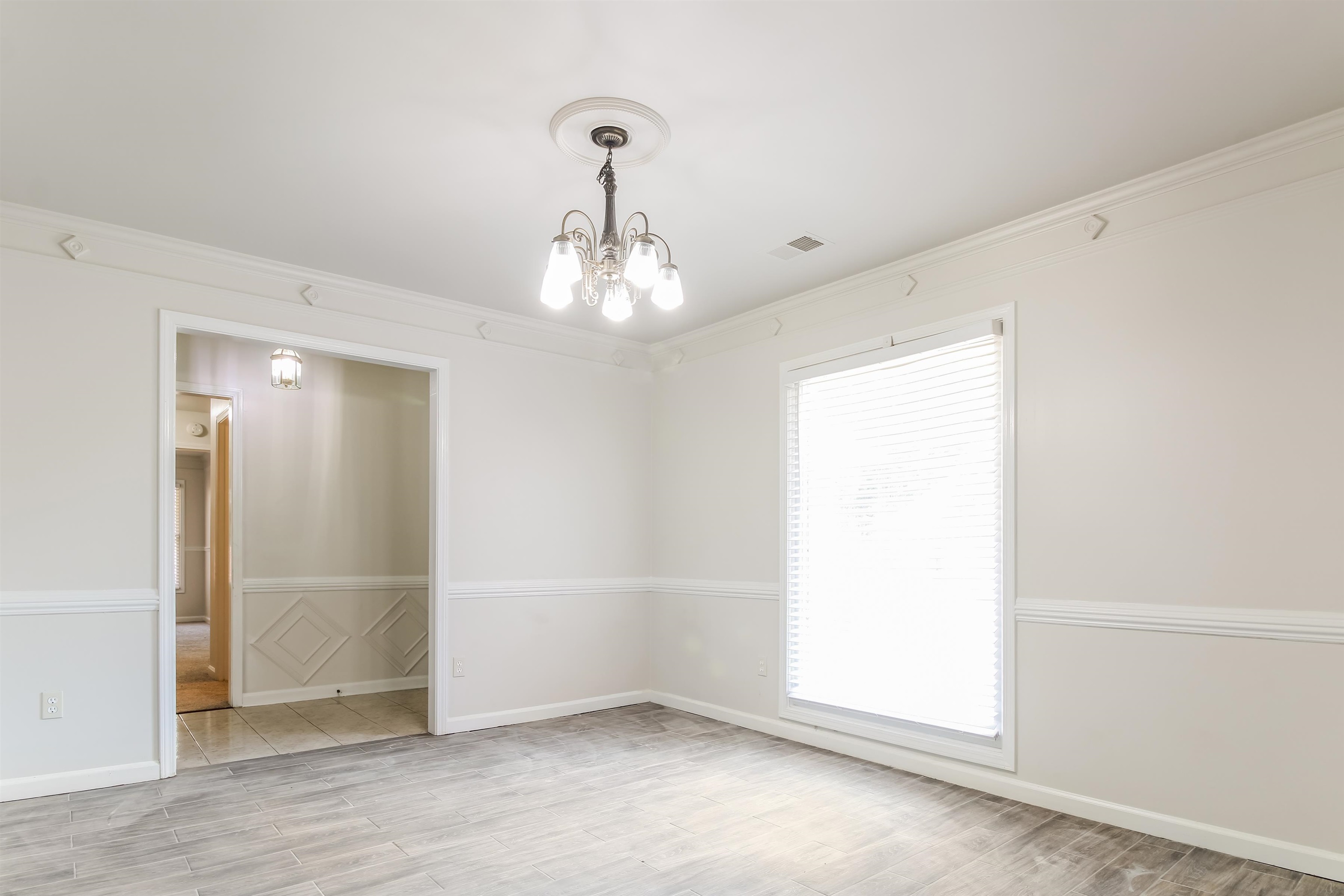 8859 Raspberry Lane Memphis, TN 38016 - Photo 6 of 16 Unfurnished room featuring plenty of natural light, a chandelier, light tile patterned flooring, and ornamental molding