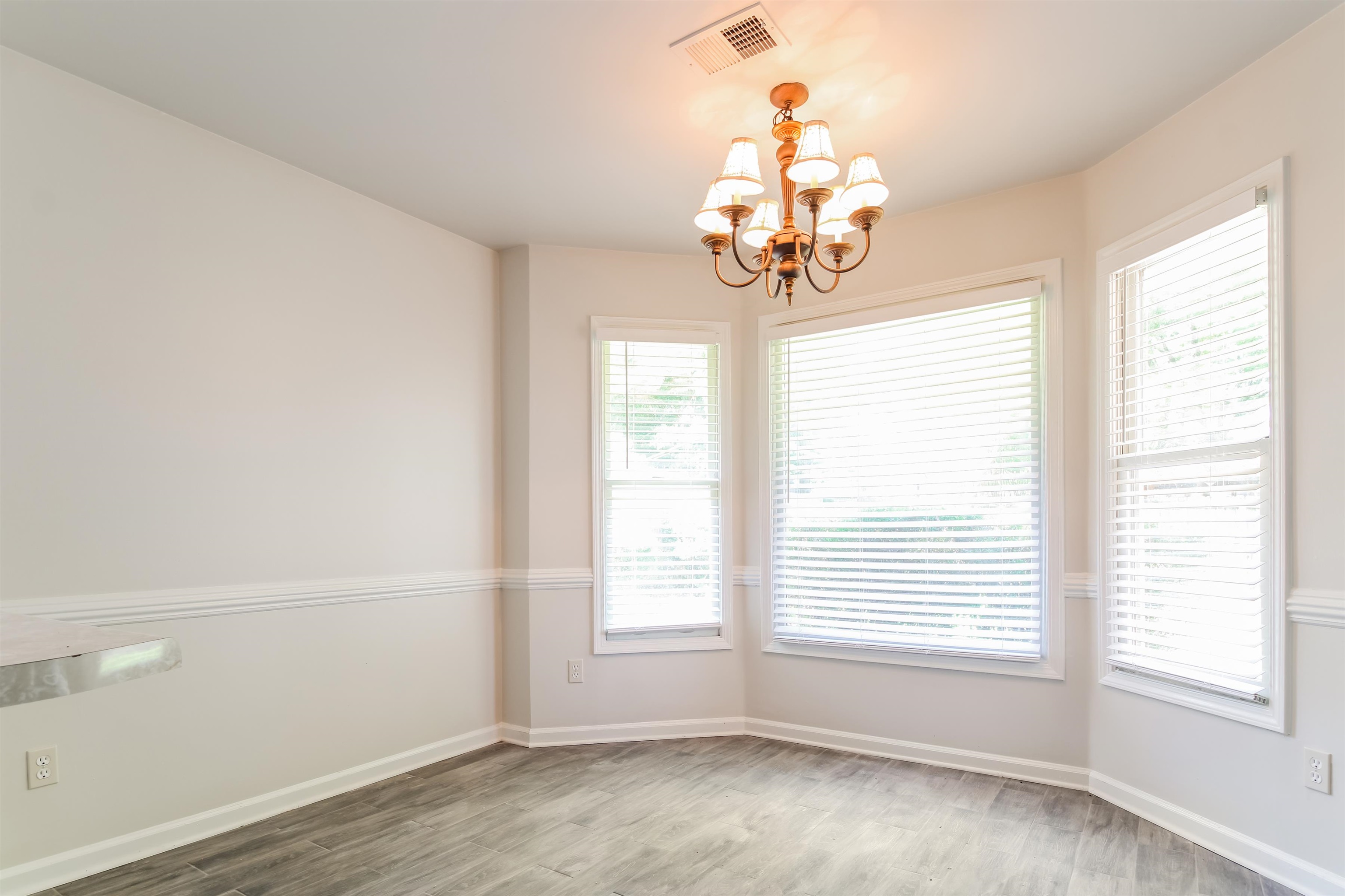 8859 Raspberry Lane Memphis, TN 38016 - Photo 7 of 16 Spare room with an inviting chandelier and wood-type flooring