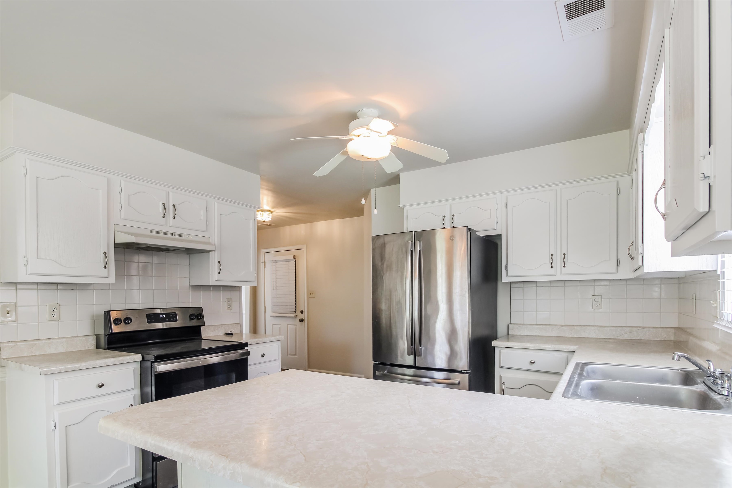 8859 Raspberry Lane Memphis, TN 38016 - Photo 8 of 16 Kitchen with sink, tasteful backsplash, stainless steel appliances, and white cabinets