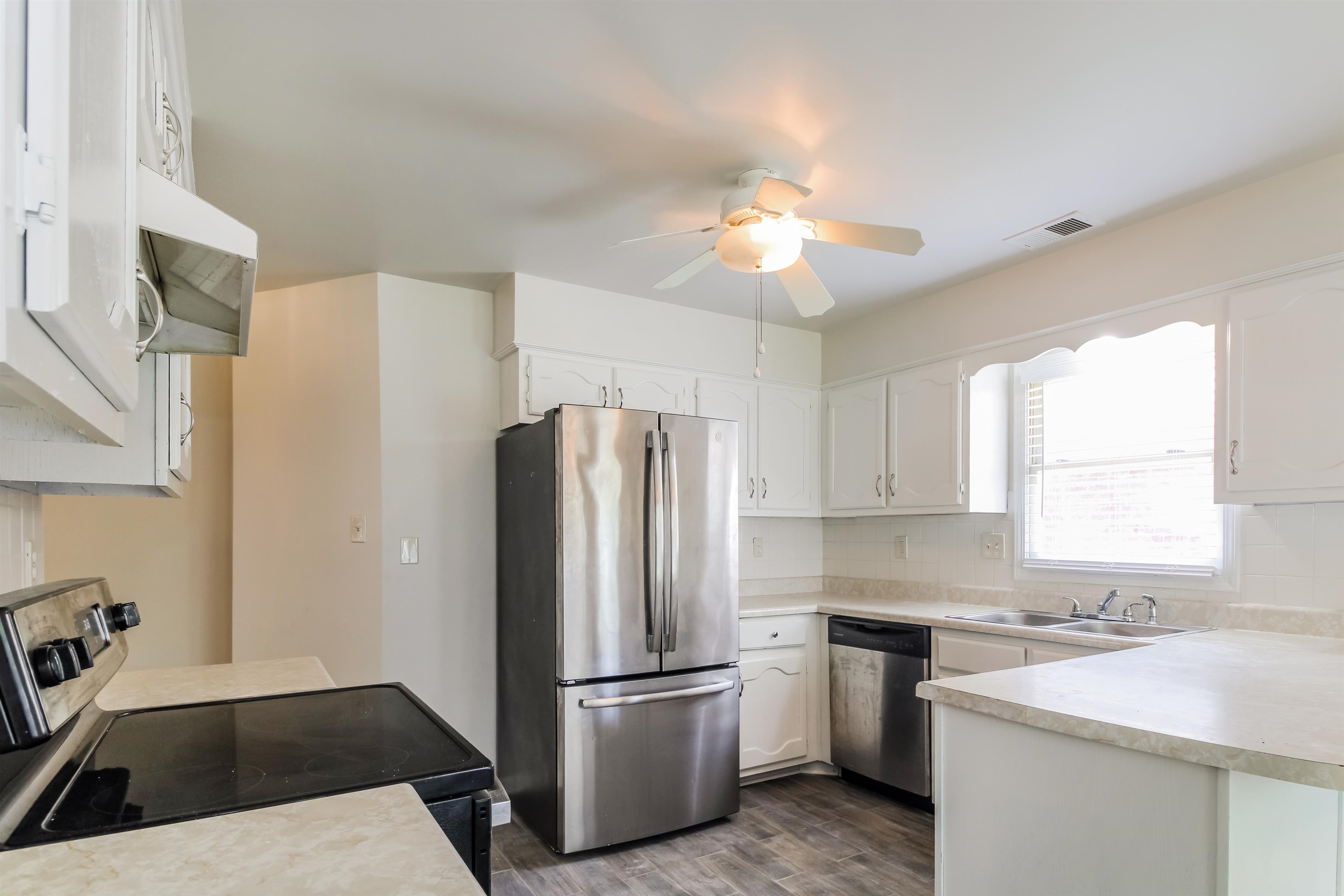 8859 Raspberry Lane Memphis, TN 38016 - Photo 9 of 16 Kitchen featuring appliances with stainless steel finishes, white cabinets, decorative backsplash, dark hardwood / wood-style floors, and ceiling fan
