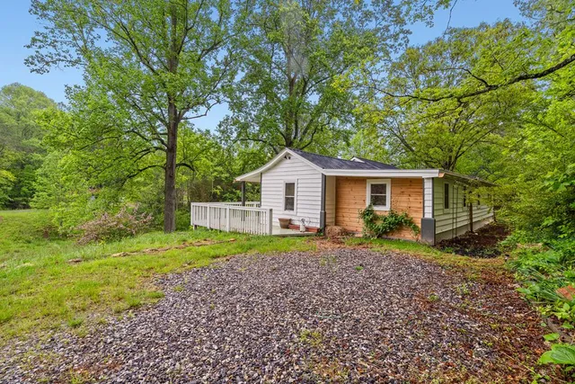 a view of a house with a yard and large trees
