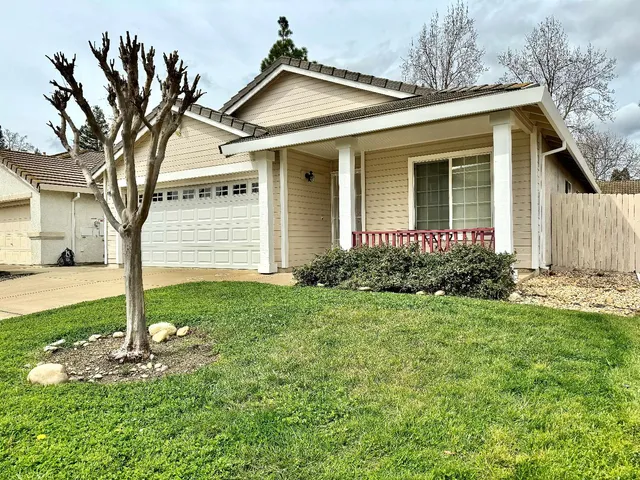 a view of a white house with a small yard and large tree