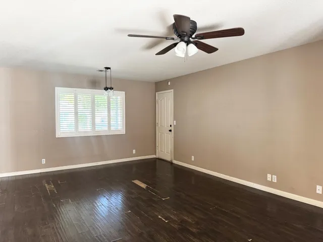 a view of a big room with wooden floor a ceiling fan and windows