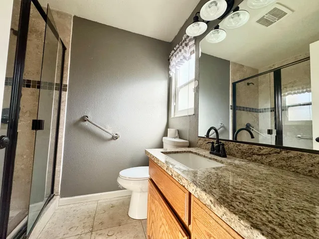 a bathroom with a granite countertop sink toilet and shower