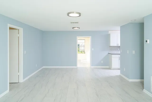 a view of an empty room with a window and wooden floor