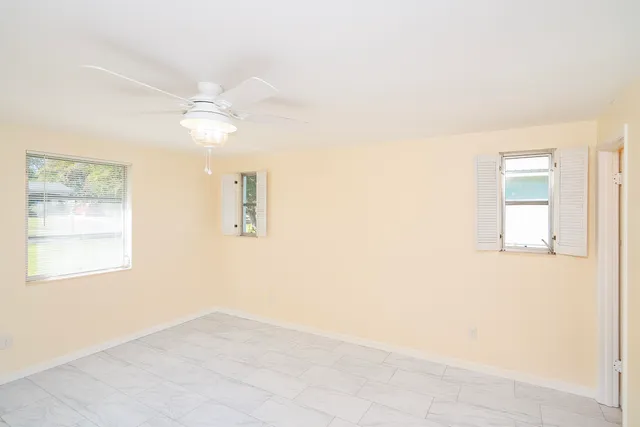 an empty room with windows and fan