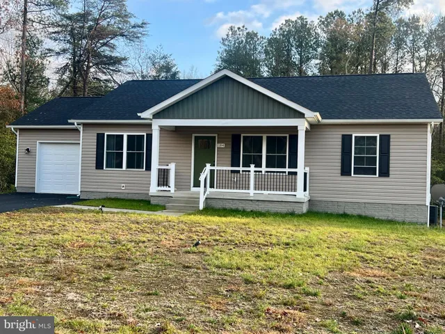 a white house that has a small yard and a large tree in front of it
