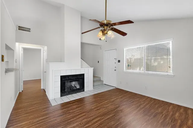 a view of an empty room with wooden floor fireplace and a window