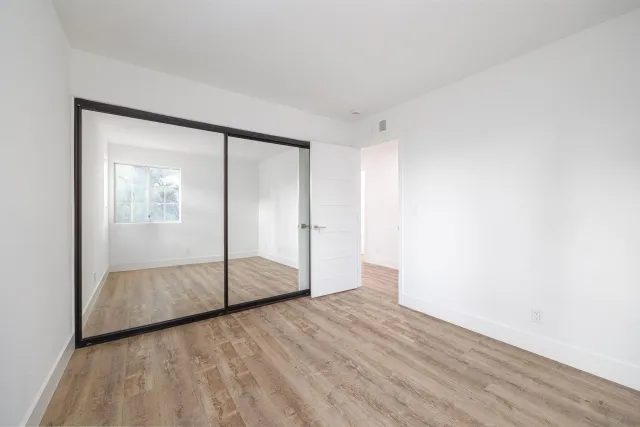 a view of empty room with wooden floor